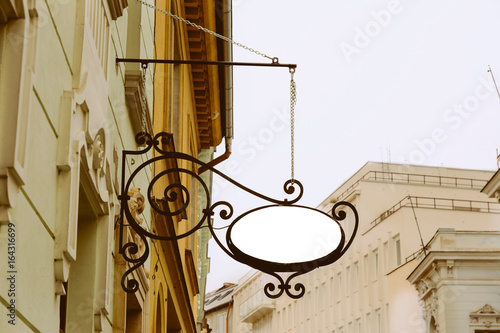Blank Oval signboard  hanging from wrought iron bracket