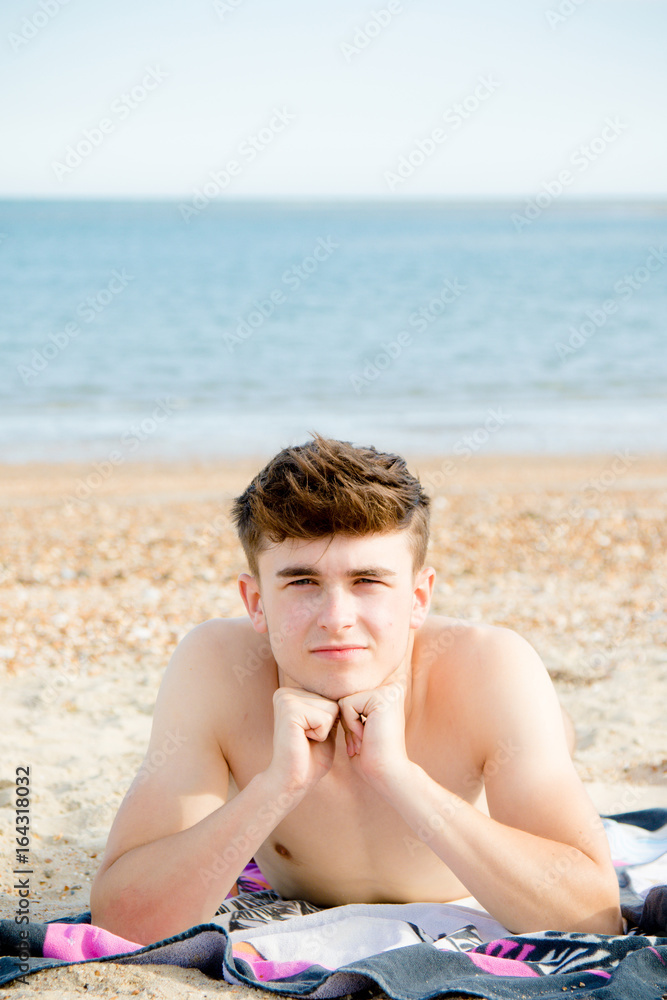 Teenage boy laying on a stoney beach Teenage boy laying on a stoney beach