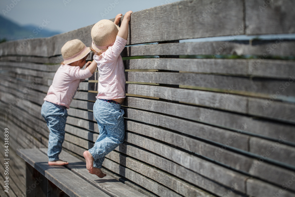Identical twin girls on a wooden bench barefoot Identical twin girls on a wooden bench barefoot
