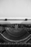 black and white image of antique typewriter and blank paper
