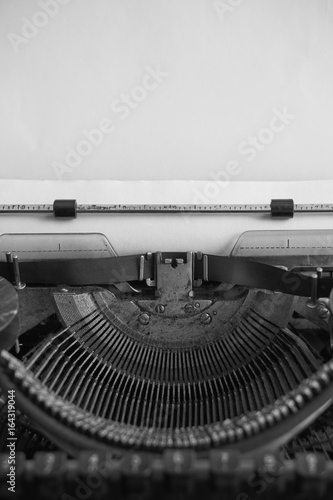 black and white image of antique typewriter and blank paper
