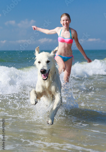 happy girl playing with a dog on the beach