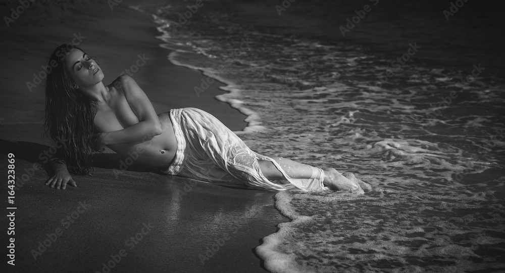 Fototapeta premium Elegant Beautiful brunette woman with long white skirt on the beach in spain