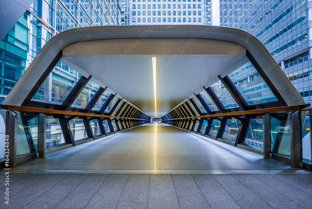 Fototapeta premium London, England - Public pedestrian cross rail footbridge at the financial district of Canary Wharf with skyscrapers