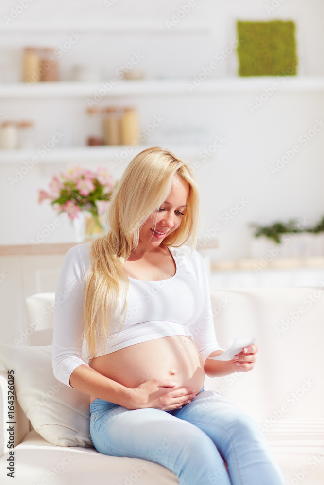 happy pregnant woman with ultrasound picture of future baby, sitting on sofa at home happy pregnant woman with ultrasound picture of future baby, sitting on sofa at home