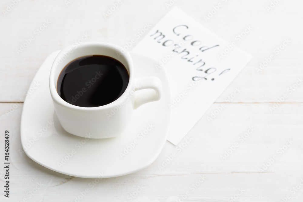 Simple morning with white cup of coffee for better half with 'good morning' message on white wooden table Simple morning with white cup of coffee for better half with 'good morning' message on white wooden table