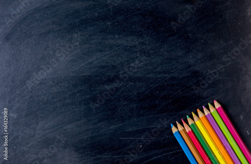 Bottom of colorful pencil crayons against a blackboard background, crayons is a supplies and stationery, concept ecucation and back to school photo