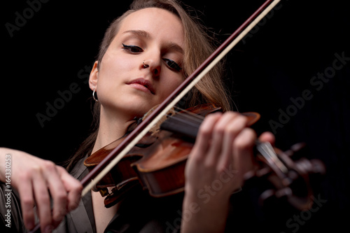 serious pretty woman playing violin on black