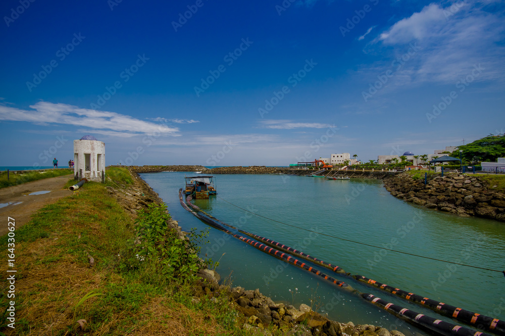 Obraz premium MANABI, ECUADOR - JUNE 4, 2012: Stagnant water with a water pumping machine at Same, Ecuador in a beautiful blue sky in a sunny day