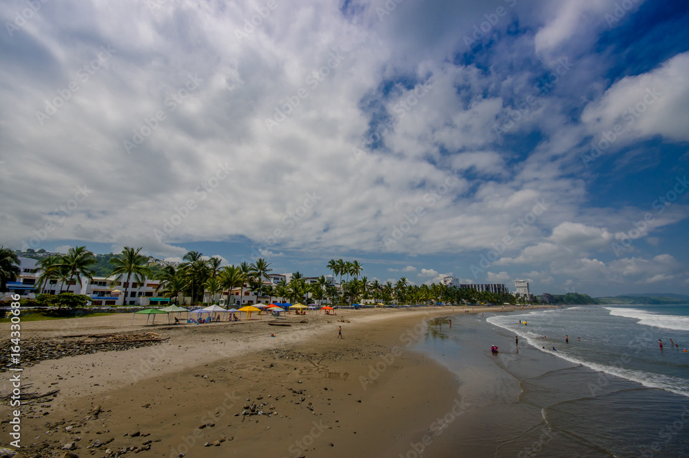 SAME, ECUADOR - MAY 06 2016: Beautiful view of the beach with sand, and builsings behind in a beautiful day in with sunny weather in a blue sky in Same, Ecuador