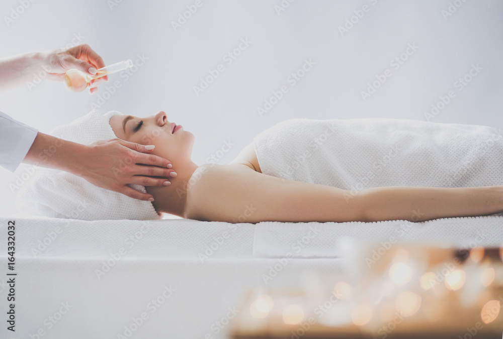 Naklejka premium Young woman lying on a massage table,relaxing with eyes closed. Woman. Spa salon