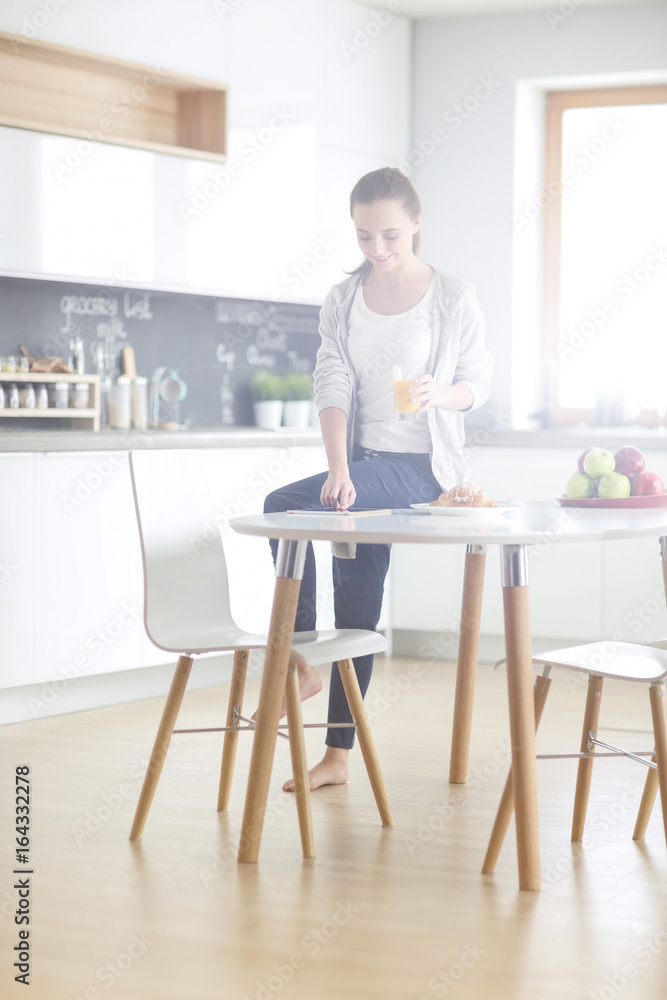 Young woman with orange juice and tablet in kitchen. Young woman with orange juice and tablet in kitchen.