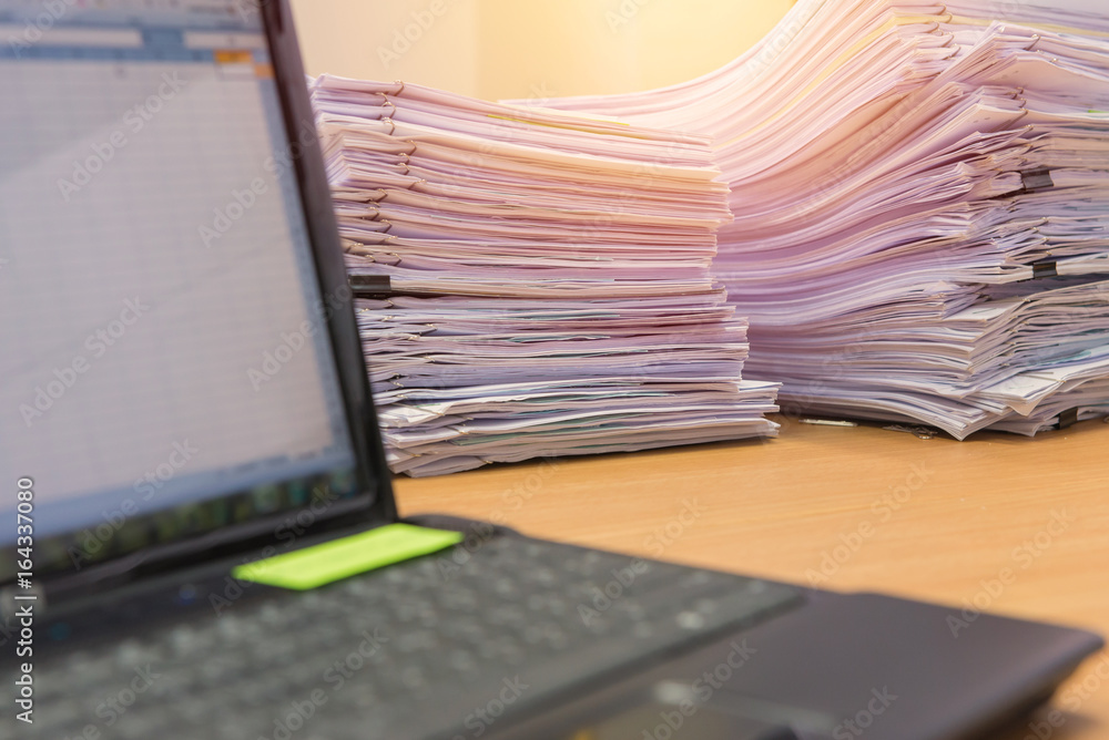 computer notebook and documents on desk stack up high waiting to be managed computer notebook and documents on desk stack up high waiting to be managed