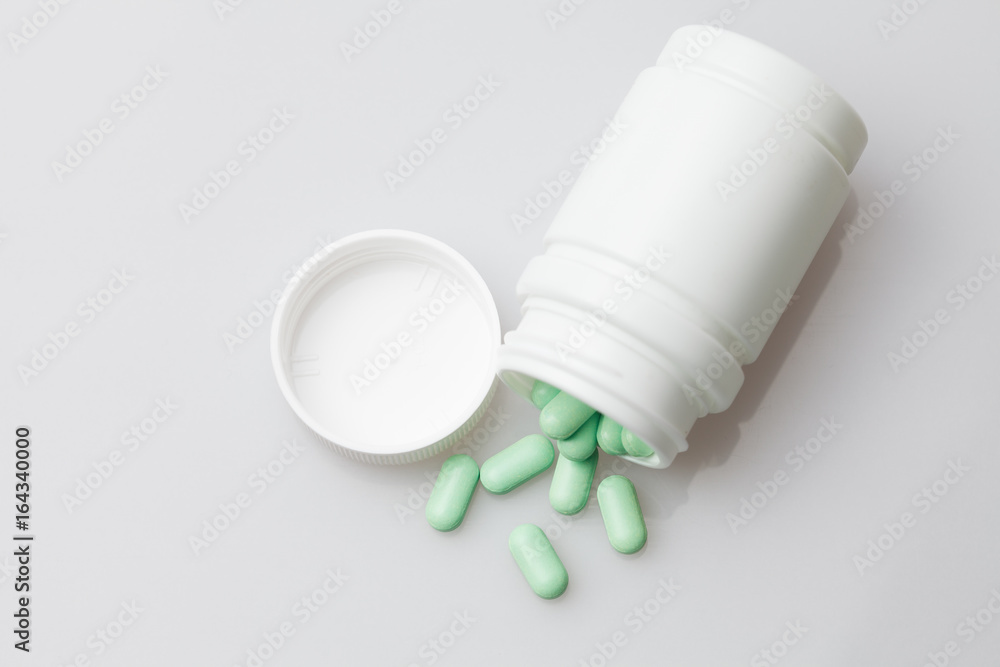 Pills and pill bottle on white background