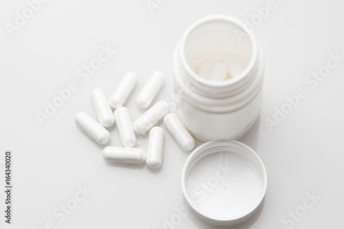 Pills and pill bottle on white background