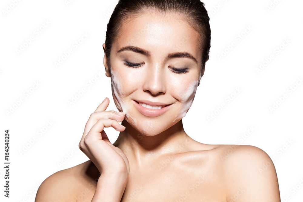 Close-up face of beautiful young woman with cleansing foam on skin. Isolated on white background