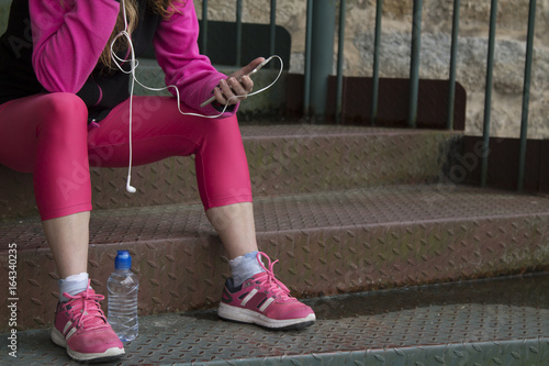 Woman athlete listening music with mobile phone