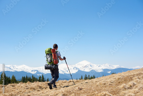 Man with a backpack and trekking sticks hiking in the mountains copyspace landscape view beauty achievement success sport active lifestyle concept