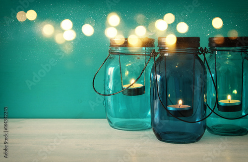 Obraz na plátně vintage decorative magical mason jars with candle light on wooden table
