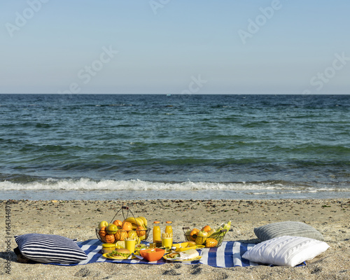 Summertime. A picnic on the beach. Burgers and pitas, vegetables and fruits.