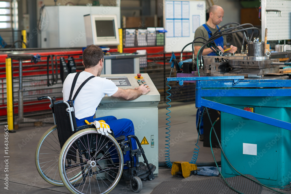 disabled worker in wheelchair in factory and colleague - obrazy, fototapety, plakaty 