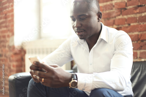 Image of african american professional businessman in business formal attire on his mobile cell smartphone.