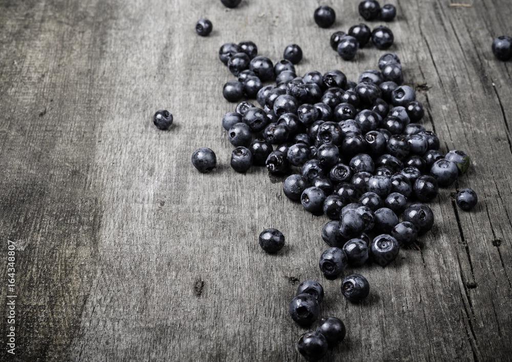 Blueberries collected manually scattered on the old gray wooden board. Toned Blueberries collected manually scattered on the old gray wooden board. Toned