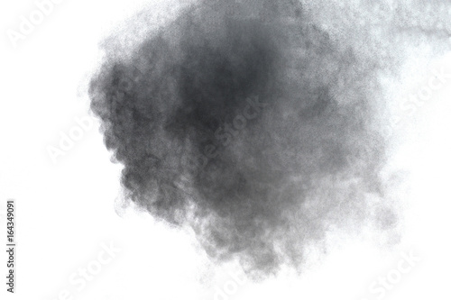 Black powder explosion. Closeup of black dust particles explode isolated on white background.