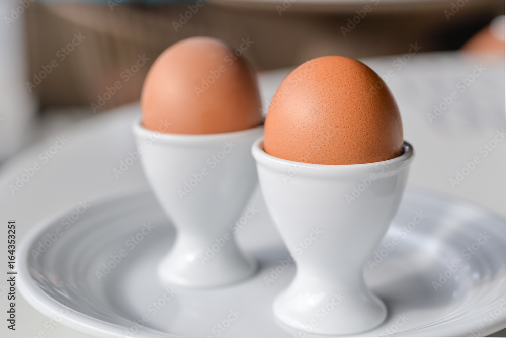 Boiled eggs in egg cup on a white plate Boiled eggs in egg cup on a white plate