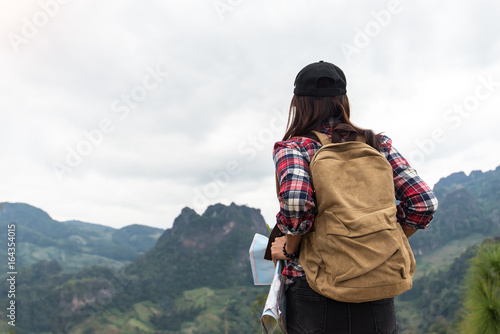 Rear view of female hiker looking at map in forest,Hiker woman look binoculars on the mountain, background blue sky, Thailand, select and soft focus