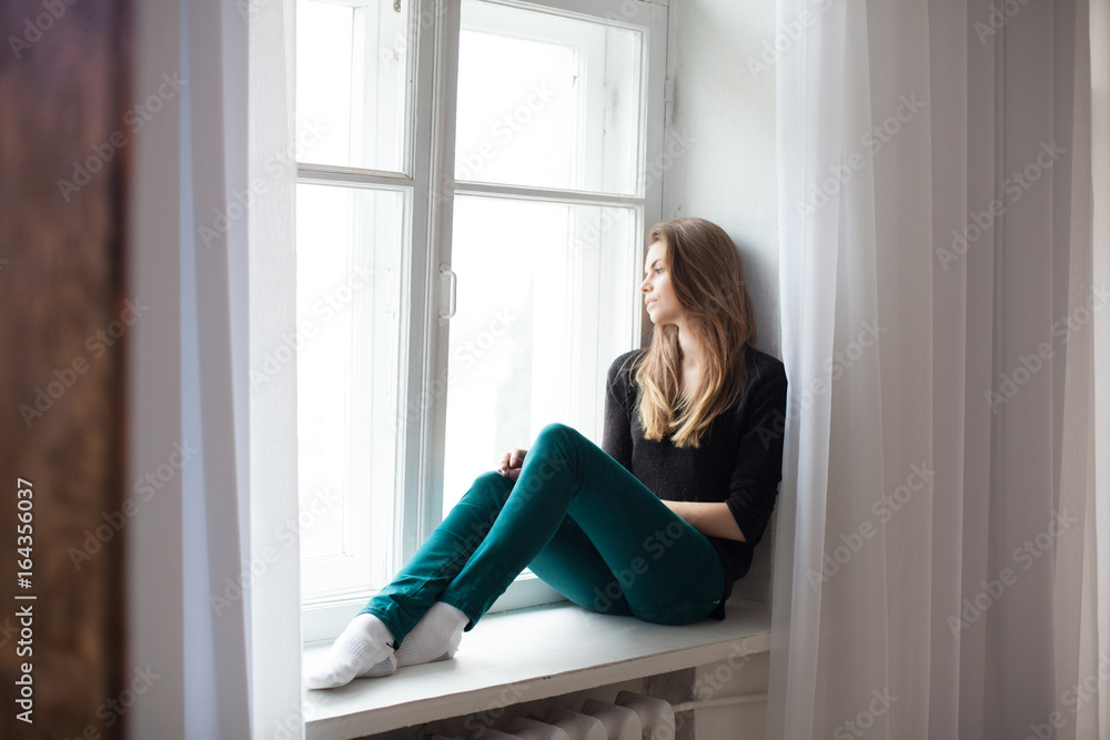 the girl sitting by the window watching the street the girl sitting by the window watching the street