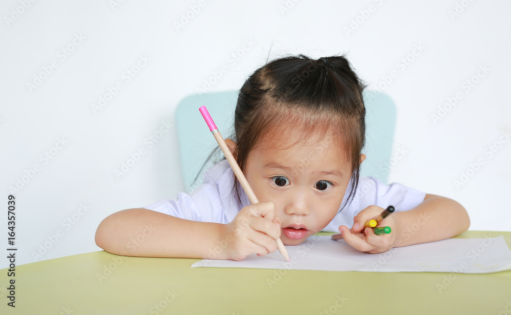 Asian child in school uniform with pencil writing on table isolated on white background. Asian child in school uniform with pencil writing on table isolated on white background.