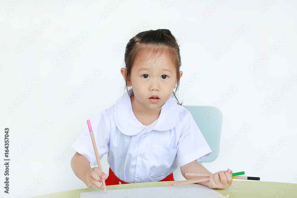 Asian child in school uniform with pencil writing on table isolated on white background. Asian child in school uniform with pencil writing on table isolated on white background.
