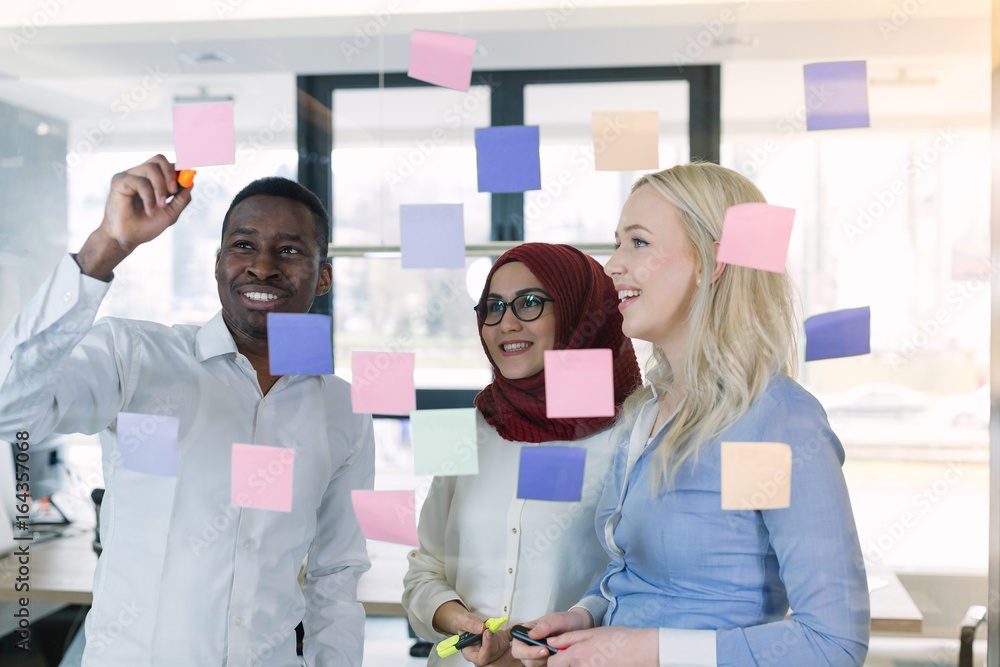 young creative startup business people on meeting at modern office making plans and projects with post stickers on glass young creative startup business people on meeting at modern office making plans and projects with post stickers on glass