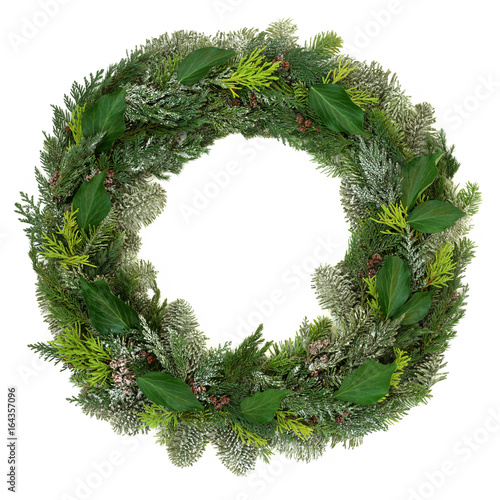 Winter and Christmas wreath decoration with snow covered natural juniper fir, blue spruce, cedar and ivy leaves on white background. photo