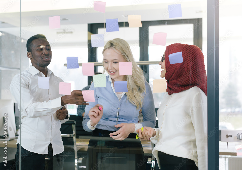 Obraz premium Smiling modern partners looking at sticky notes