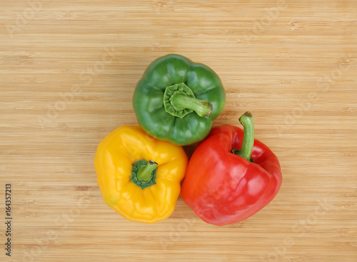 Green , red and yellow bell pepper on wood background.