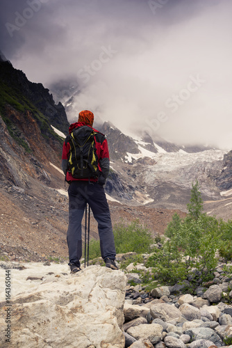 Man adventurer looks at the glacier lying in front of him