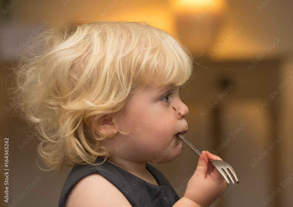 Blond girl with chocolate on face pondering whilst waiting for food Blond girl with chocolate on face pondering whilst waiting for food