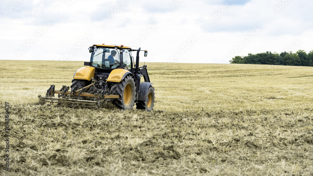 Obraz premium tracteur agricole au travail sur le champ fraichement fauché