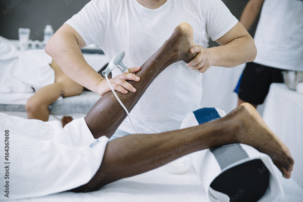 The physiotherapist treating a man using equipment for radio therapy The physiotherapist treating a man using equipment for radio therapy