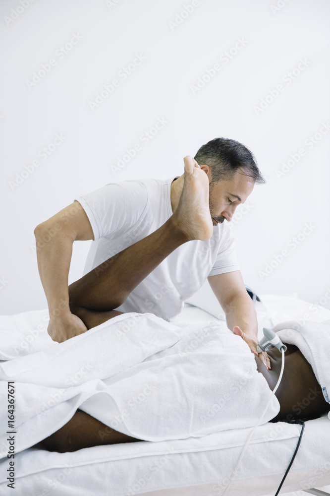 The physiotherapist treating a man using equipment for radio therapy The physiotherapist treating a man using equipment for radio therapy