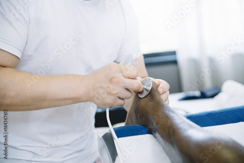 Wallpaper Mural The physiotherapist treating a man using equipment for radio therapy Torontodigital.ca