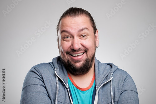 Portrait of laughing young man against grey wall. Happy guy smiling.