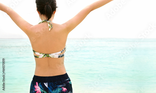Young woman hands up on the beach near the sea. Wearing swimsuit. Freedom and happy. Ko Lipe, Thailand. Back view. Close up.