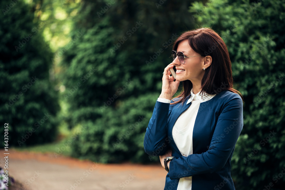Woman outdoors in park talking on mobile phone Woman outdoors in park talking on mobile phone