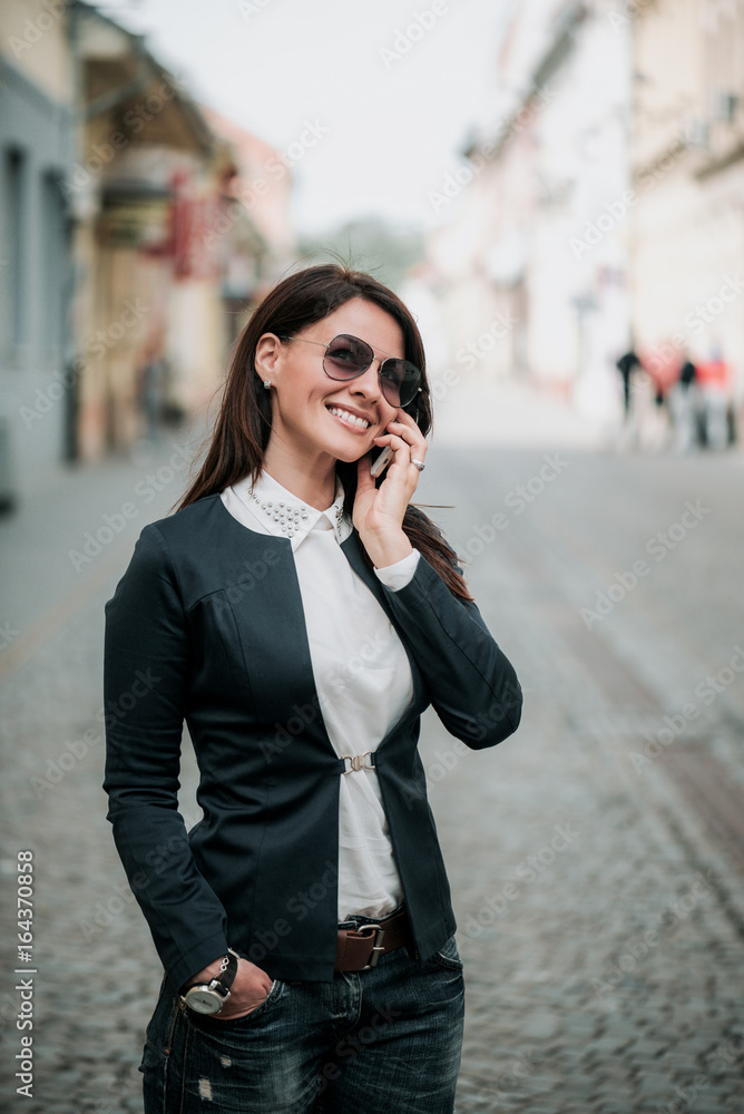 Happy young woman talking on mobile phone at city street lifestyle portrait. Happy young woman talking on mobile phone at city street lifestyle portrait.