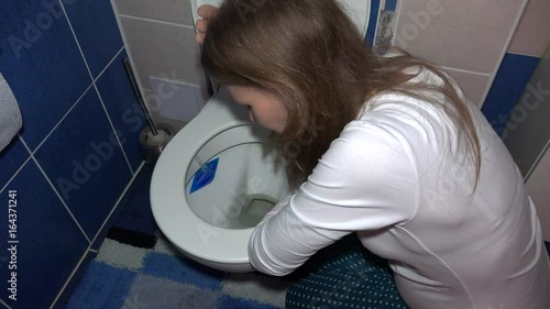 vomiting woman in bathroom in morning. Sad female sickness in pregnancy time photo