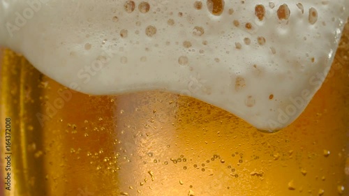 Glass of beer close-up with froth in slow motion