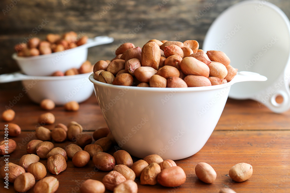 Peanuts in white measuring cup on wooden background. Peanuts in white measuring cup on wooden background.